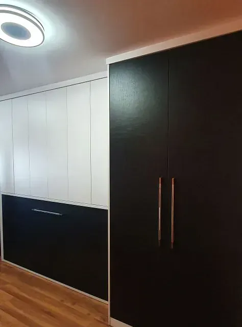 Un dormitorio con armarios en blanco y negro y una luz de techo.