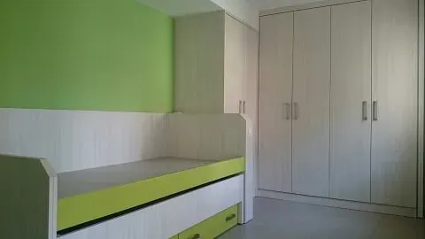 Un dormitorio con litera, armarios y paredes verdes.