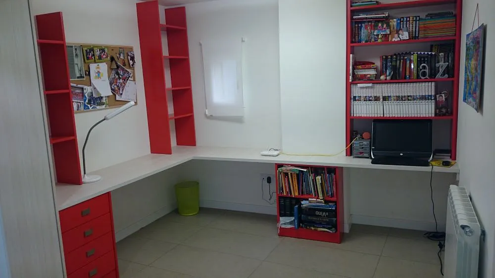 Una habitación con dos escritorios y estantes llenos de libros.