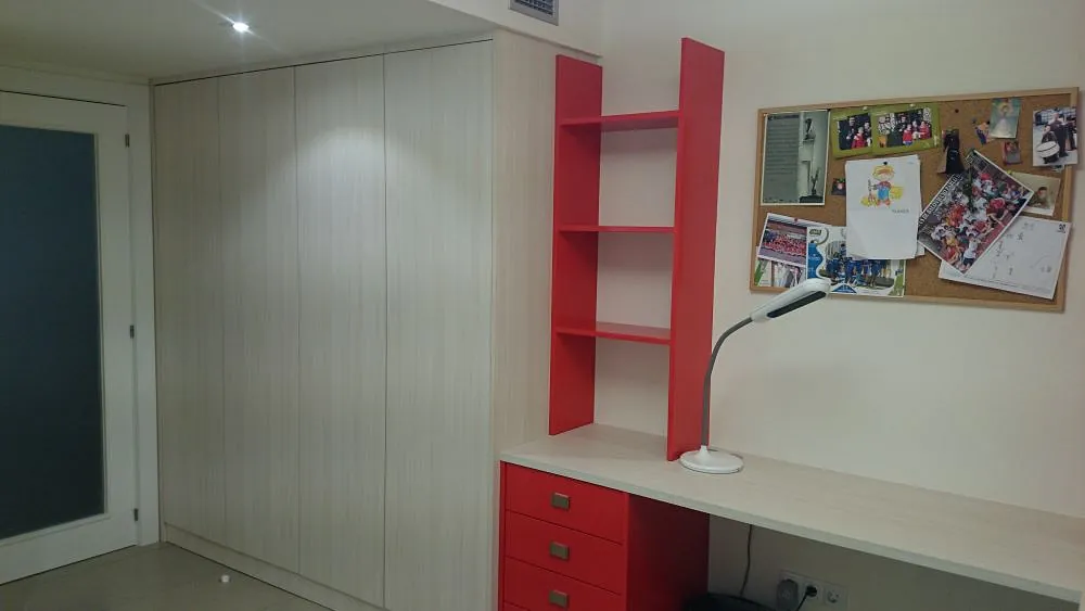 Una habitación con un escritorio, estantes y una lámpara.