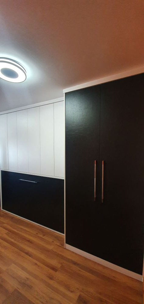 Un dormitorio con armarios en blanco y negro y suelo de madera.