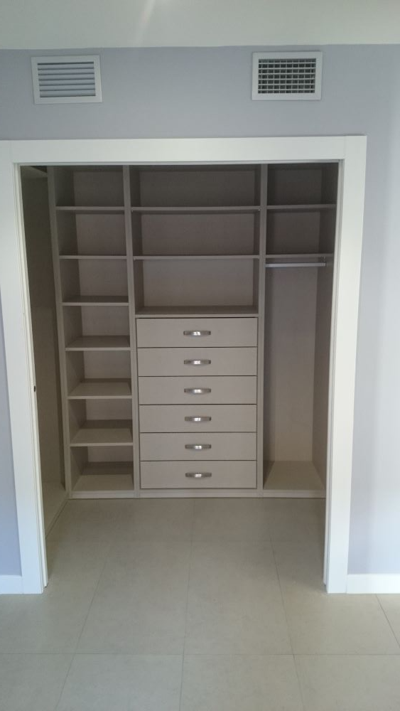 Un vestidor con cajones y estantes en un dormitorio.
