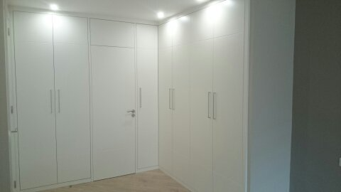Una habitación con muchos armarios blancos y una puerta.