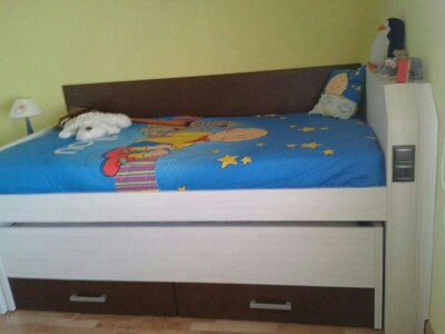 Una cama con un edredón azul y cajones debajo.