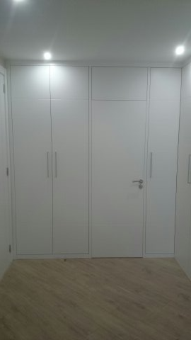 Una habitación con muchos armarios blancos y una puerta.