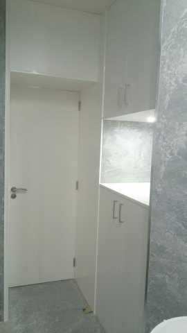 Un baño con muebles blancos, un inodoro y una puerta.