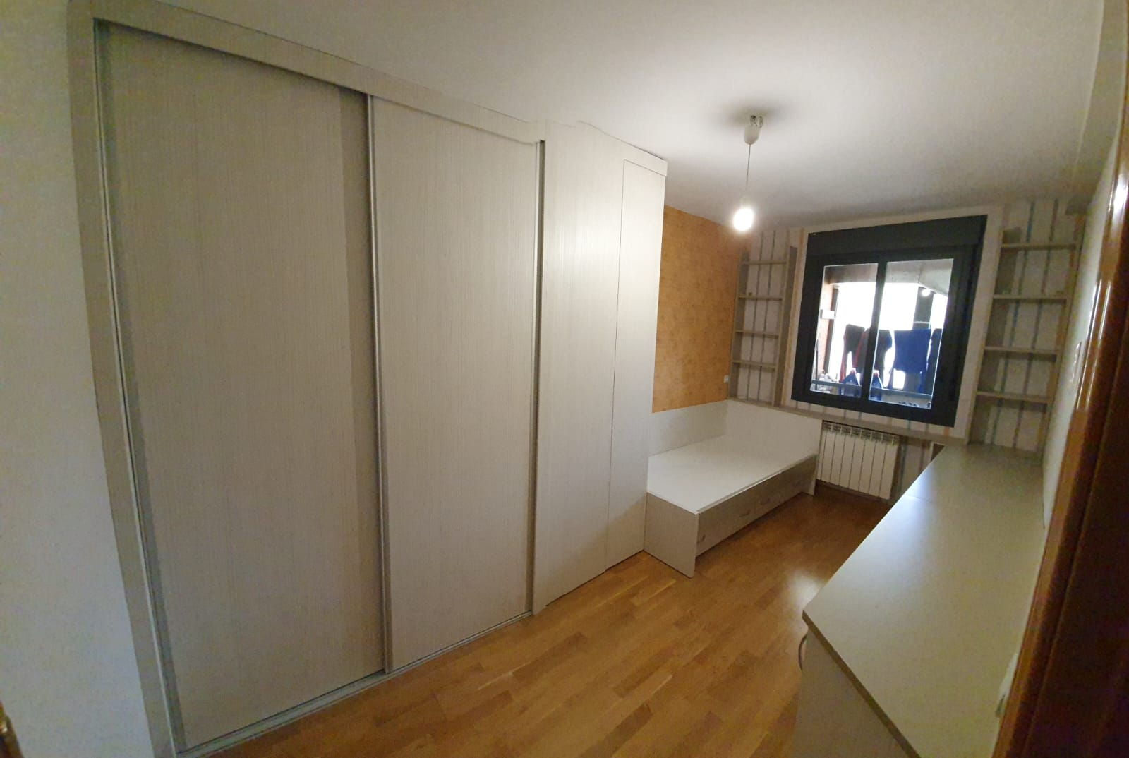 Un dormitorio con una cama, puertas correderas, estanterías y una ventana.