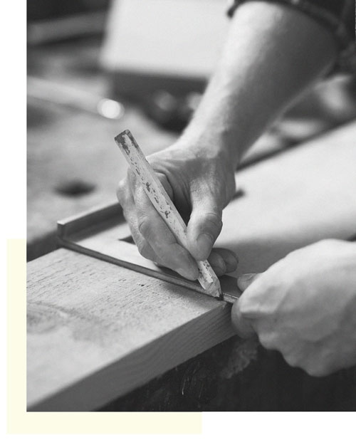 Una persona está midiendo un trozo de madera con una regla.