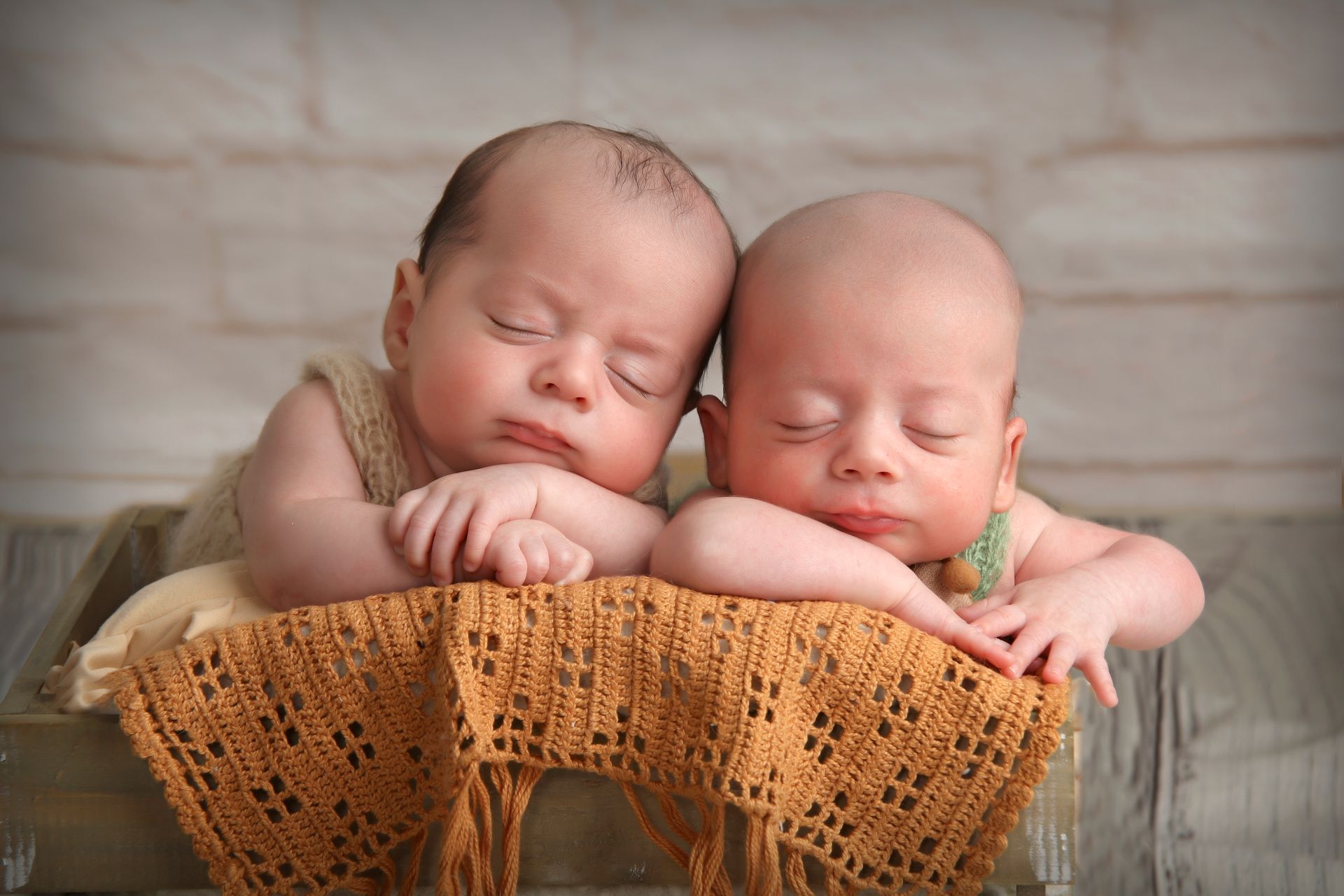 Dos bebés recién nacidos duermen uno al lado del otro en una caja de madera.