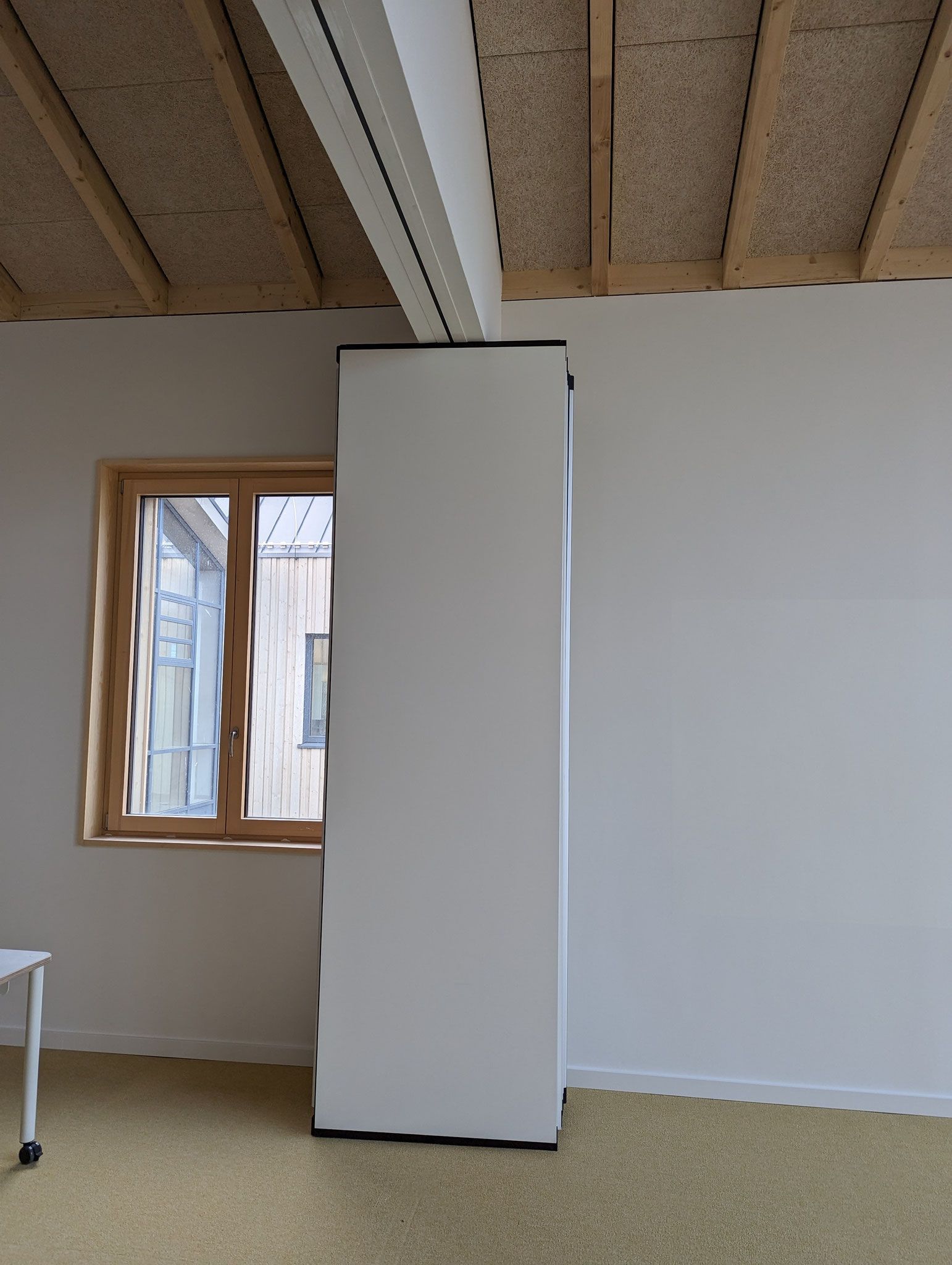 Weißer Schrank vor einem Fenster und weißer Wand. Braune Decke und gelber Boden.