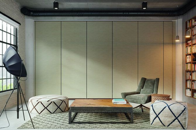 Wohnzimmer mit großen Schiebetüren, Sessel, Hocker, Couchtisch, Teppich, Fenster und Bücherregal.