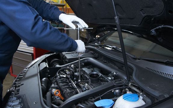 Työmies korjaamassa autoa