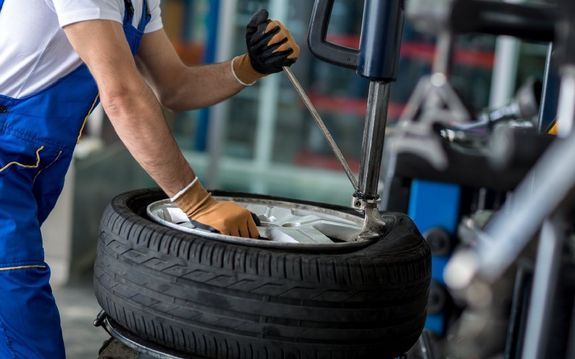 Autokorjaamon työntekijä huoltamassa autonrengasta