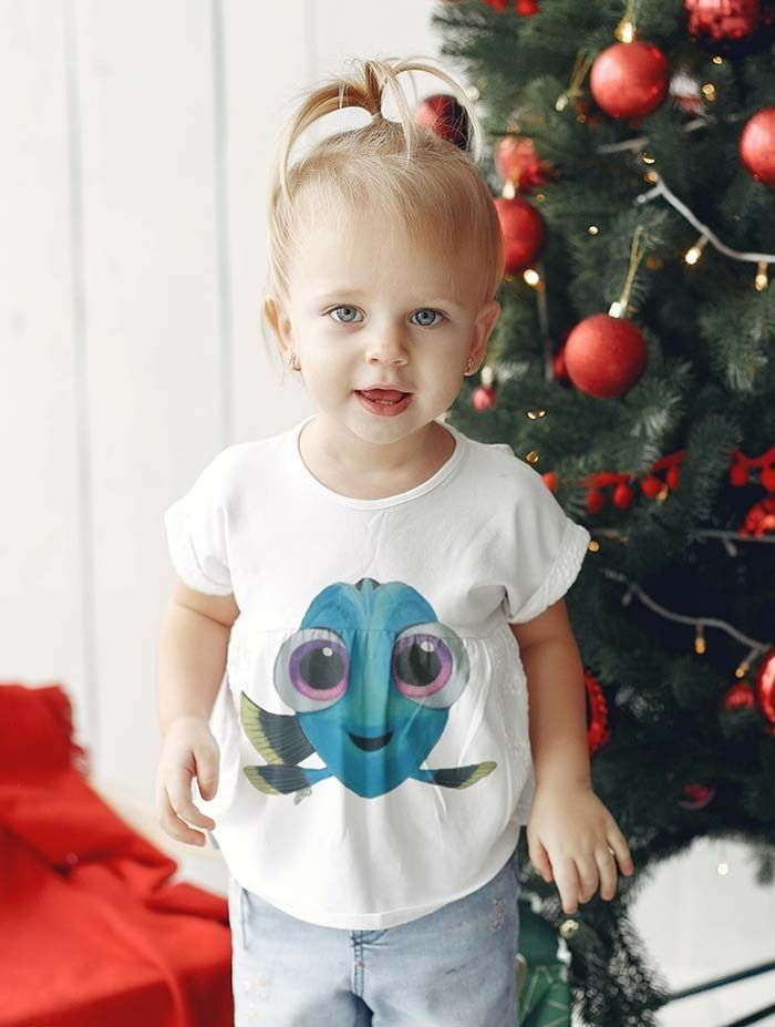 Una niña está parada frente a un árbol de Navidad.