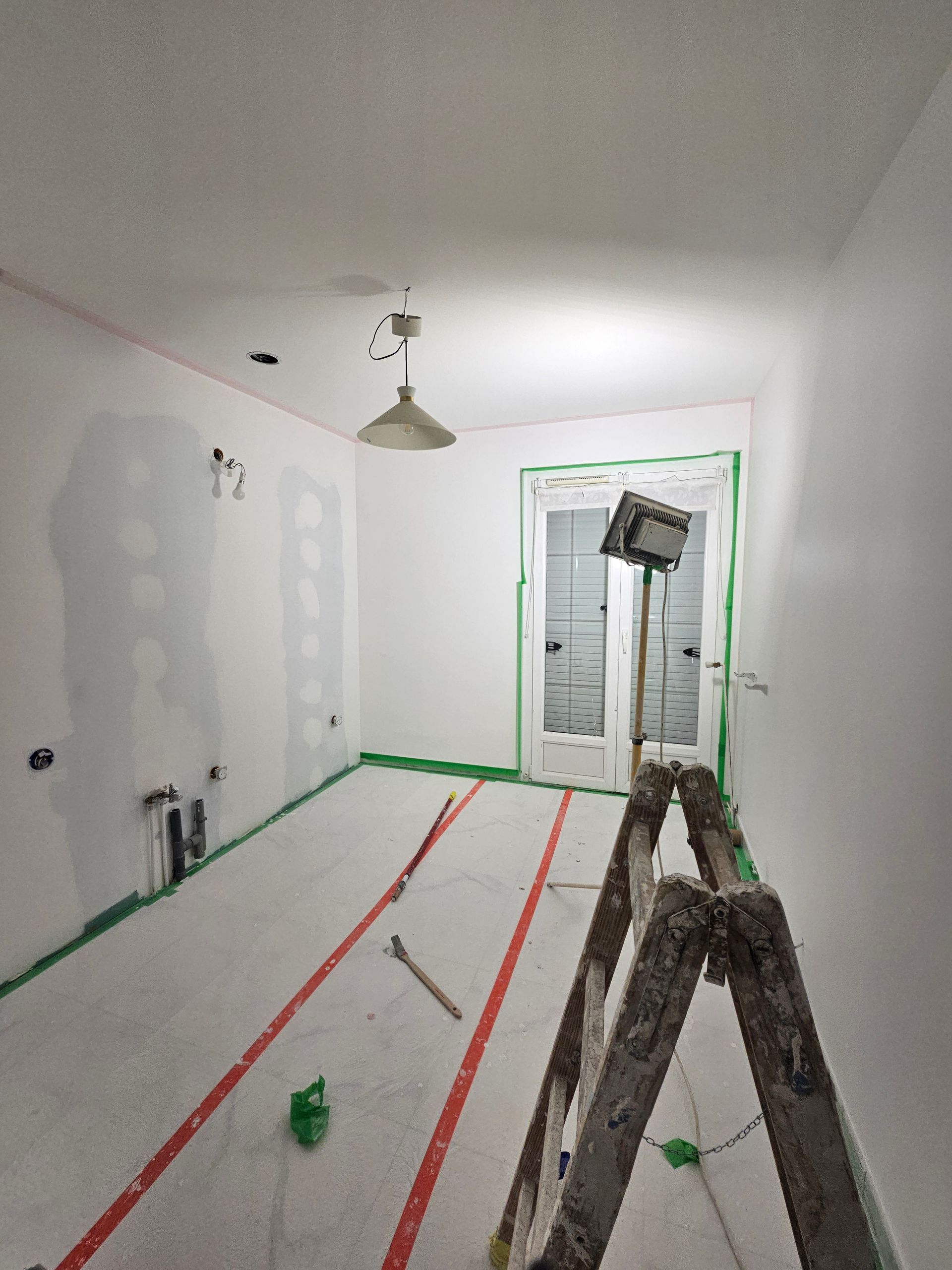 Pièce en travaux avec des rubans de masquage pour préparer la peinture de la pièce