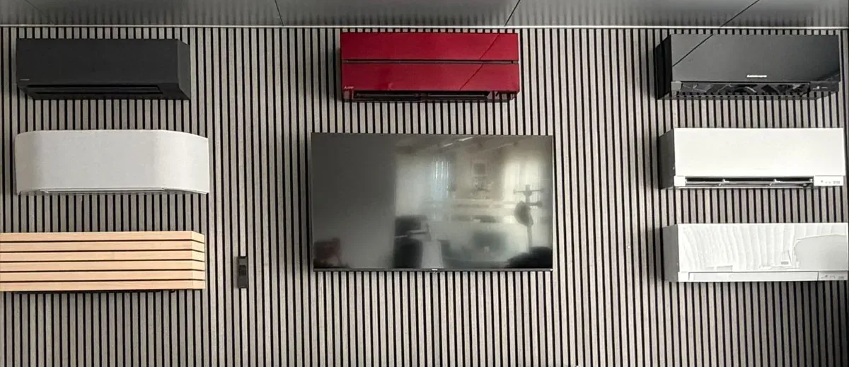 Zwei lächelnde Kollegen an einem Schreibtisch in einem Büro, hinter ihnen in Regalen blaue Ordner.