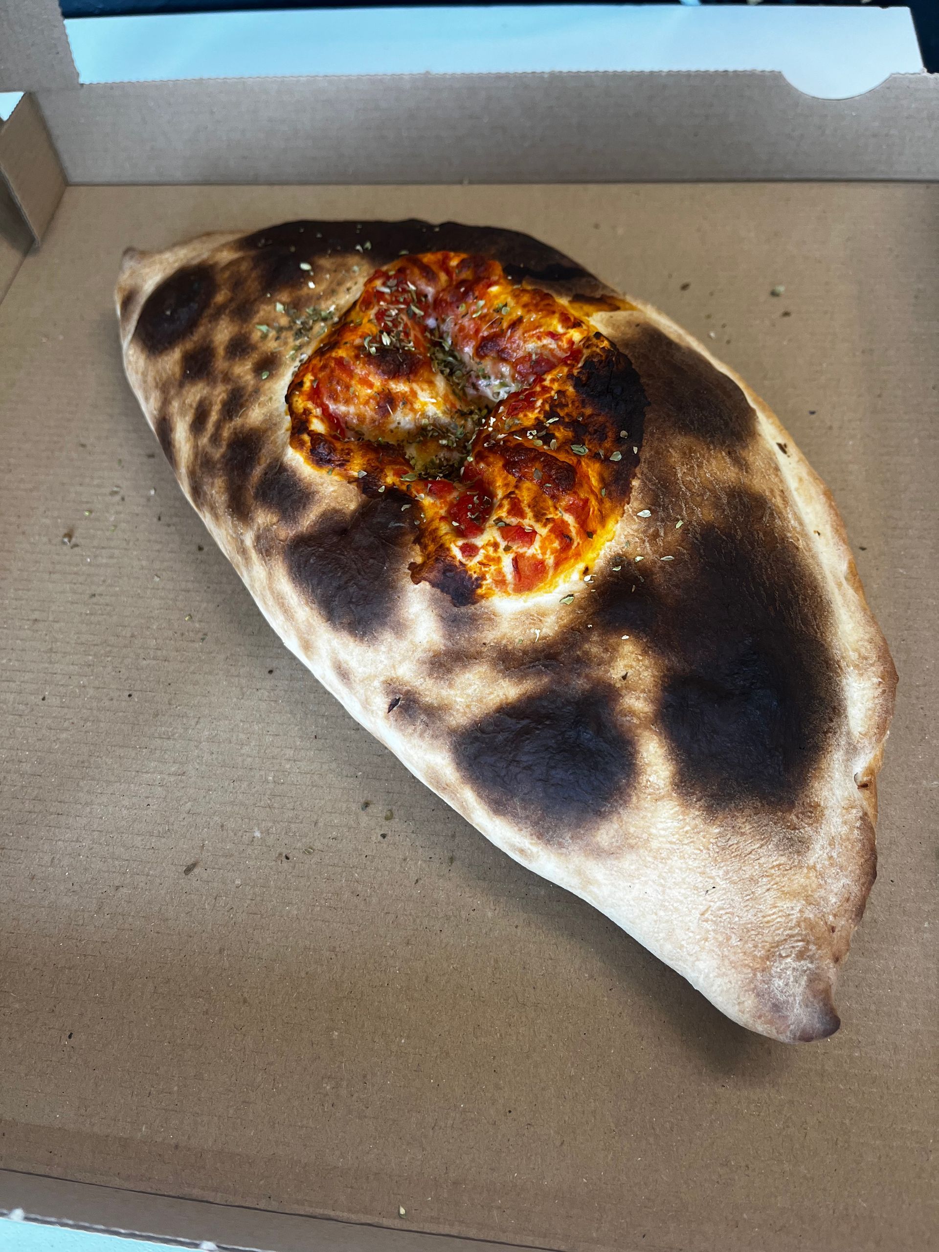 Calzone dans une boîte en carton, garni d'une petite farce rouge-orange au centre