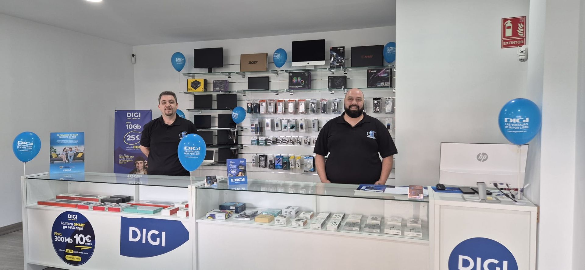 Dos hombres están de pie detrás de un mostrador en una tienda digital.