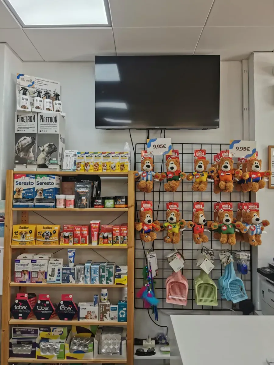 Estantería de tienda de conveniencia con aperitivos y bebidas debajo de un televisor montado en la pared
