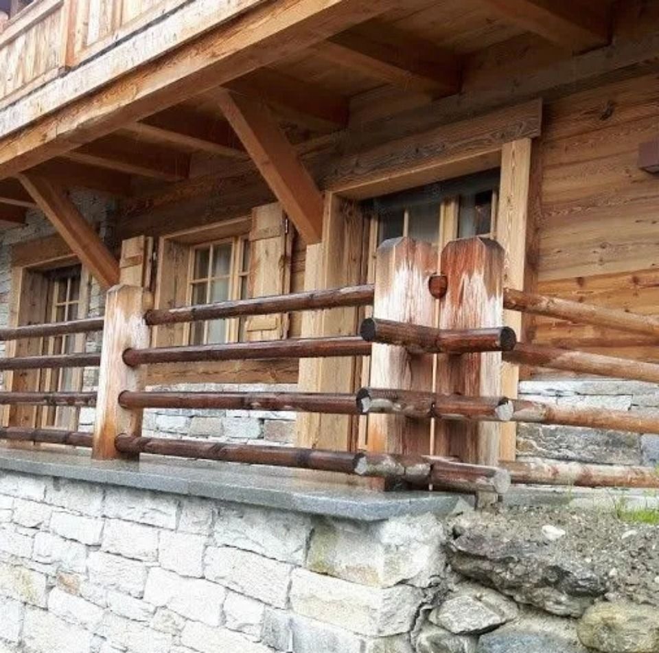 Extérieur de cabane en bois avec une base en pierre, une clôture en bois et des fenêtres.