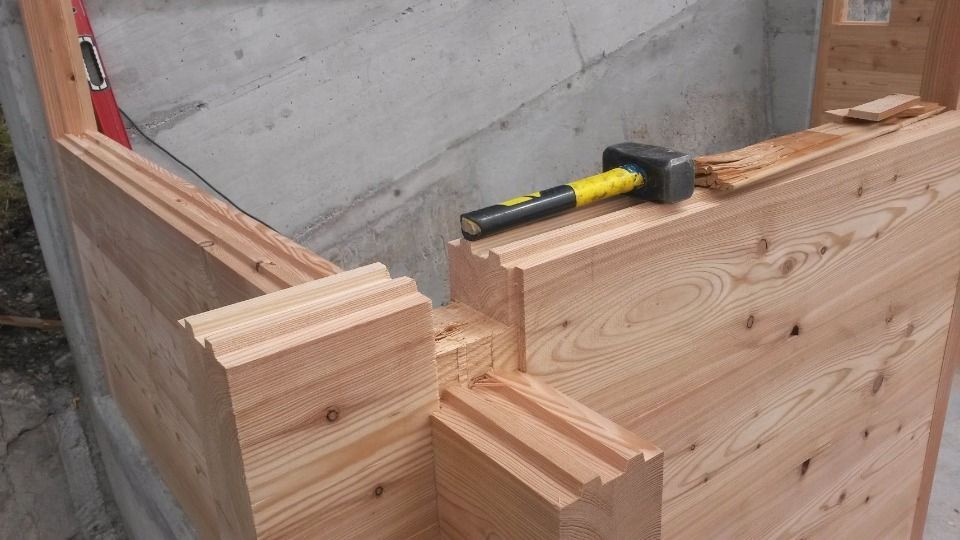 Construction à ossature bois avec maillet et niveau sur un mur en béton.