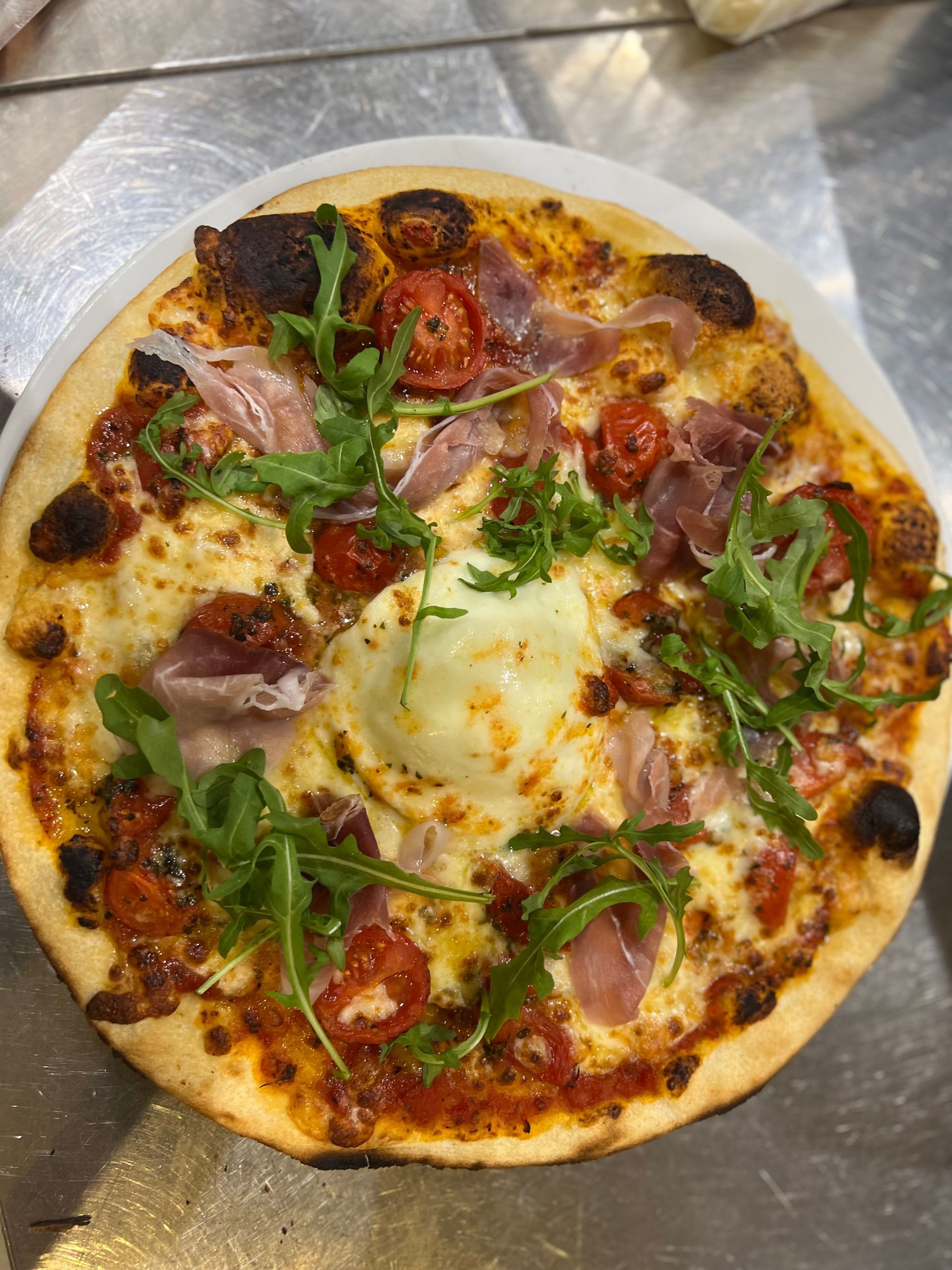 Pizza au prosciutto, aux tomates cerises et à la roquette.