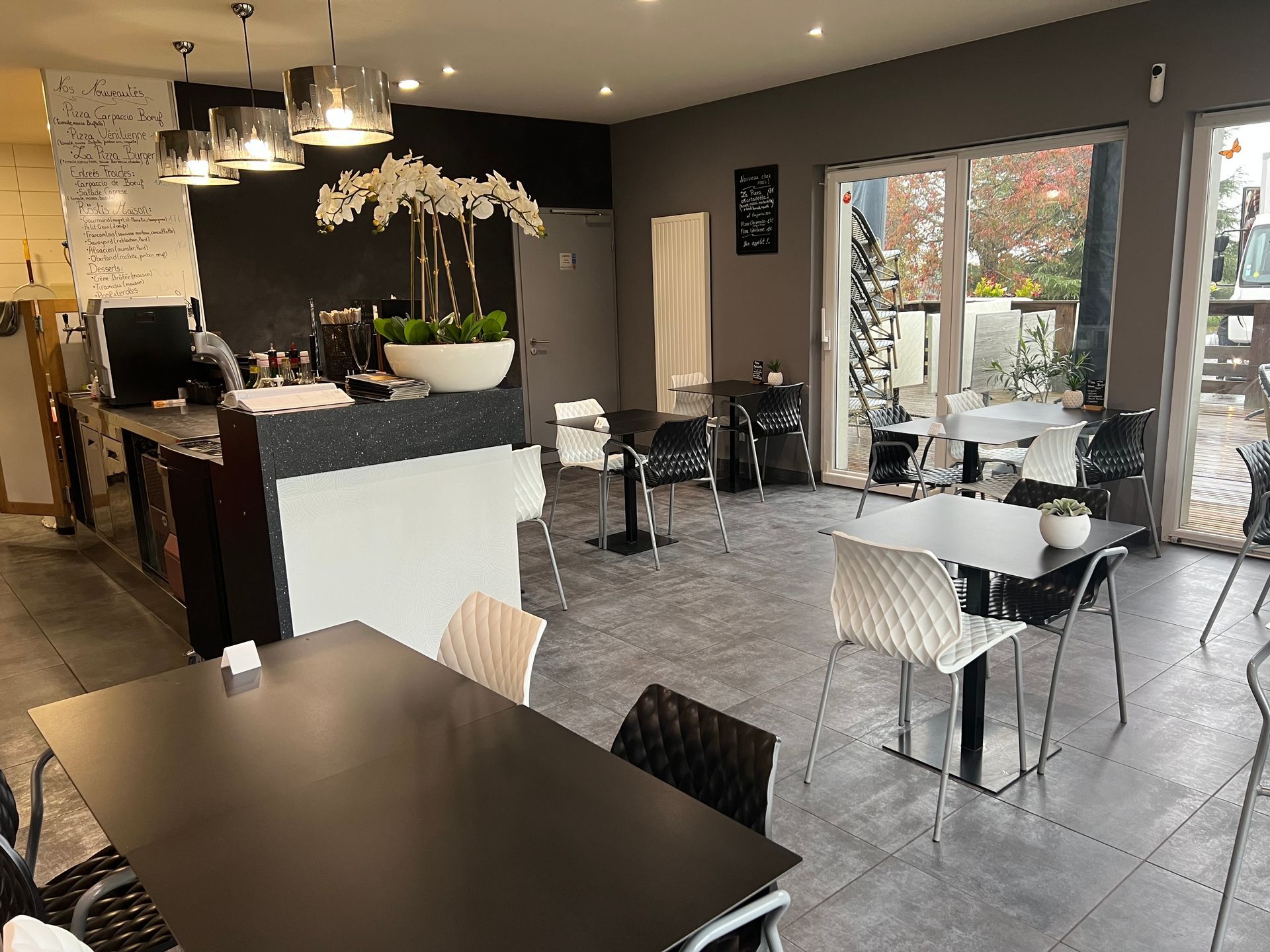 Intérieur de la pizzeria avec des tables et des chaises.