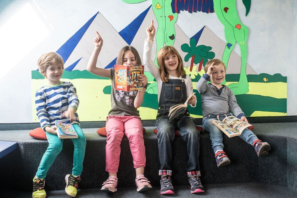 vier Kinder sitzen im Wartebereich der Praxis die spangenbauer® – Kieferorthopäde