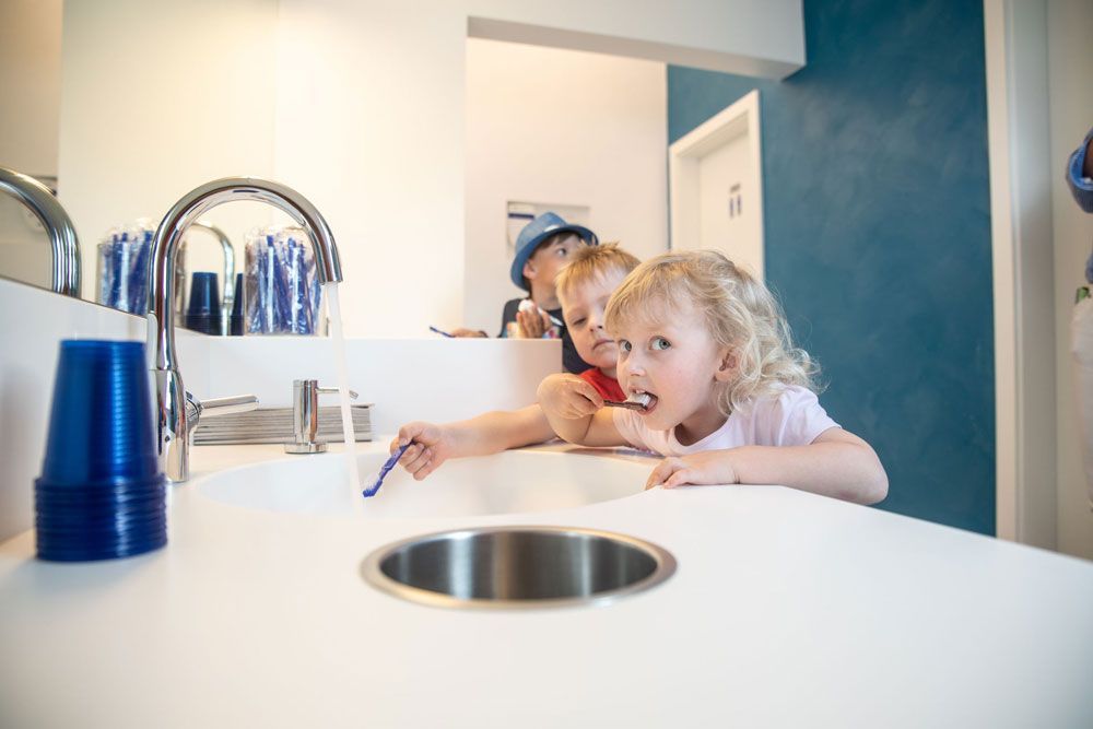 drei kleine Kinder beim Zähne putzen