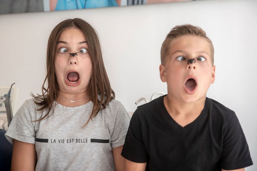 zwei Kinder mit Kunstspinnen auf der Nase