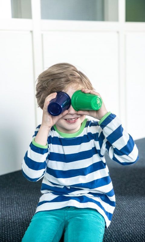 Kind hält sich zwei Becher vor die Augen