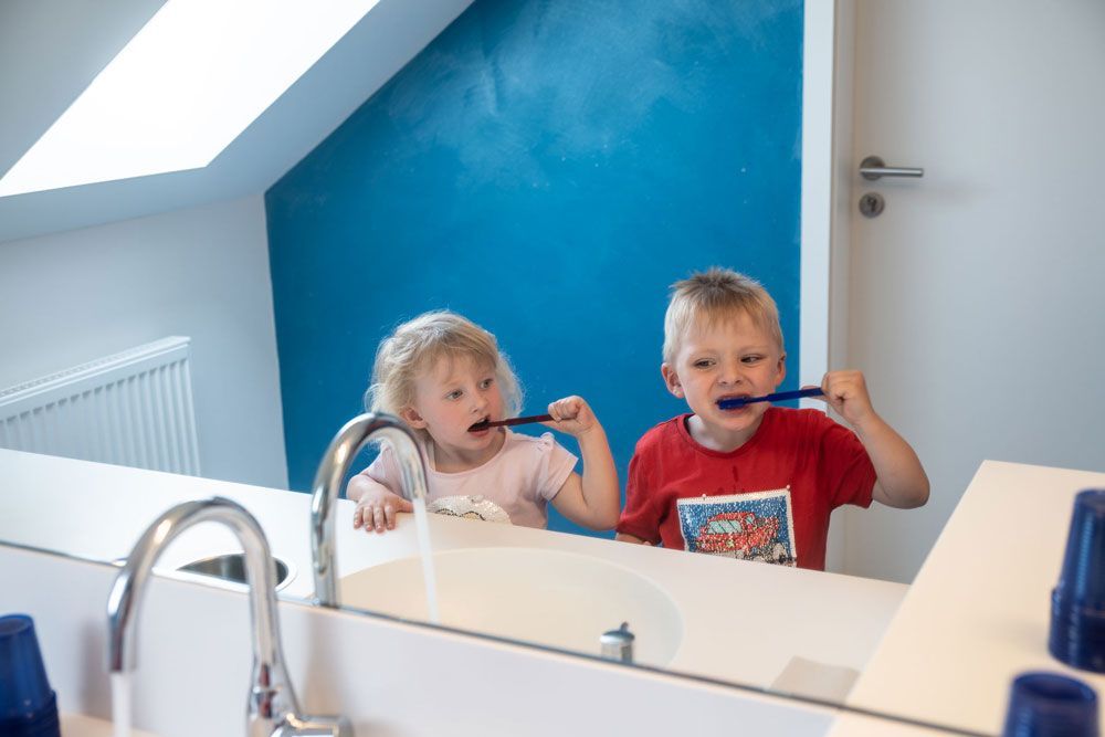 zwei kleine Kinder beim Zähne putzen