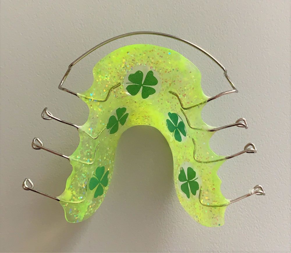 gelbe Zahnspange mit Kleeblättern