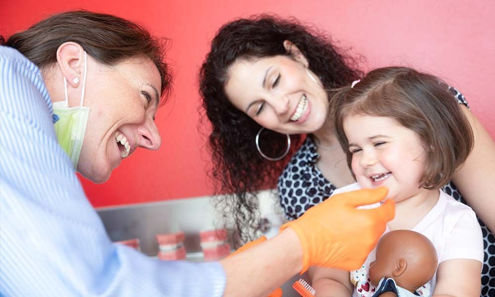 Kieferorthopädin betrachtet Gebiss eines lachenden Kindes