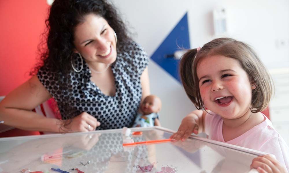 Mutter beobachtet lachendes Kleinkind