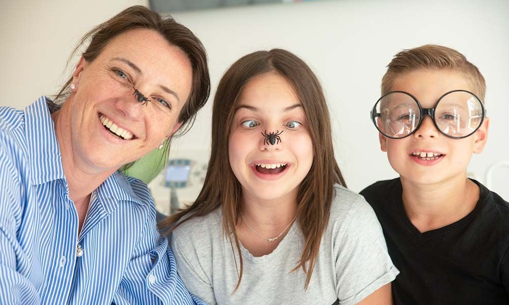 Mutter und zwei Kinder mit Plastikspinnen und großer Brille