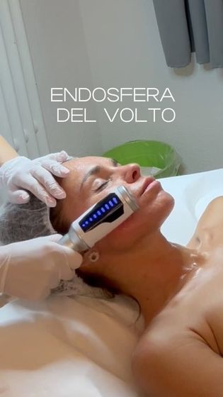 Donna che riceve un trattamento viso con un dispositivo portatile. Una mano guantata aziona il dispositivo sulla sua guancia.