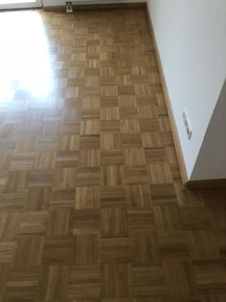 Ein Wohnzimmer mit Holzboden und weißer Wand.