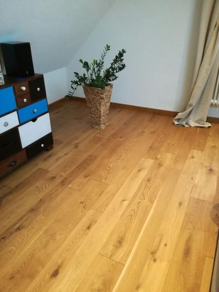 Ein Holzboden in einem Raum mit einer Topfpflanze darauf.