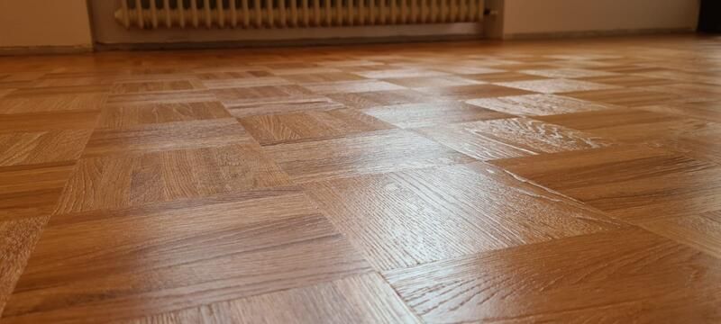 Eine Nahaufnahme eines Holzbodens mit einem Heizkörper im Hintergrund.