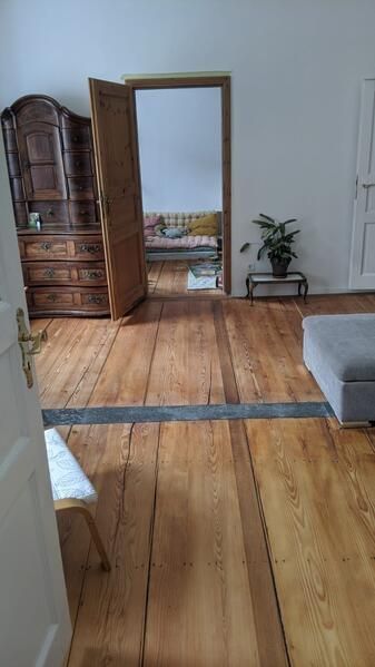 Ein Wohnzimmer mit Hartholzböden, einem Sofa und einer Kommode.