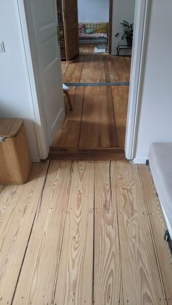 Ein Holzboden in einem Flur, der zu einem Badezimmer führt.