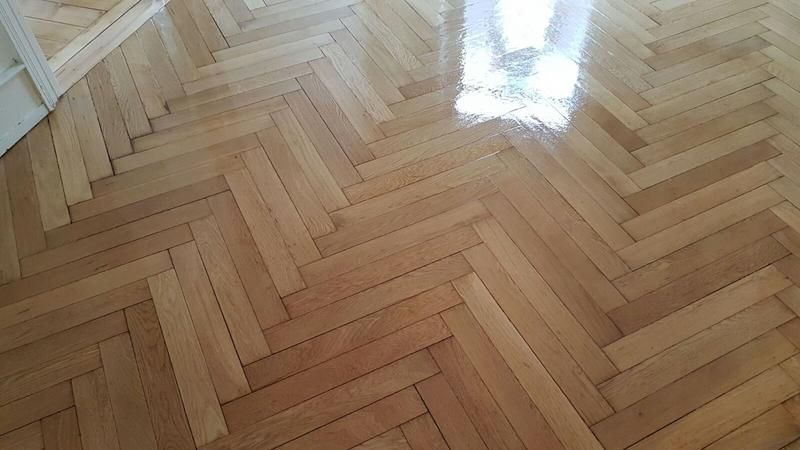 Eine Nahaufnahme eines Holzbodens mit Fischgrätenmuster.