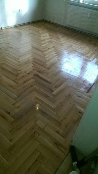Ein Holzboden mit Fischgrätenmuster in einem Raum.