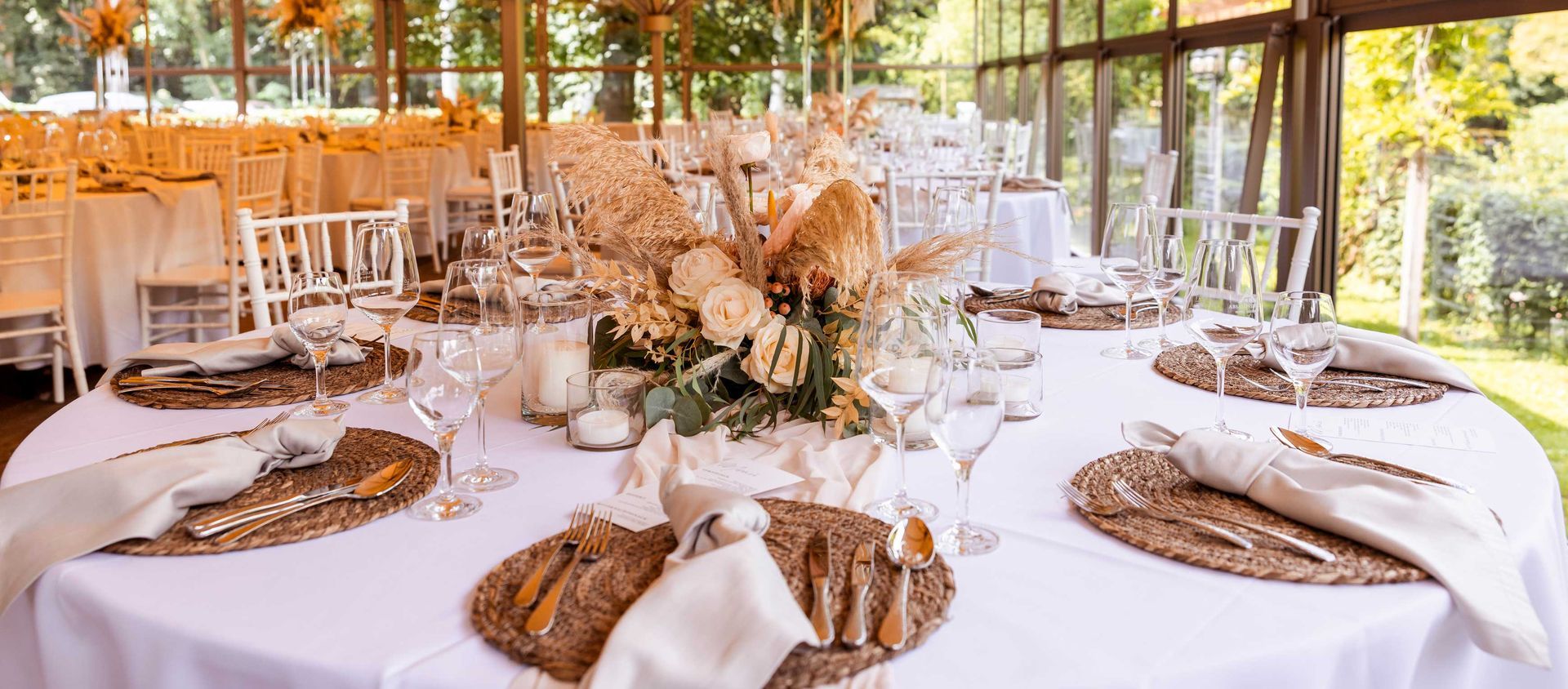 Tischdekoration für den Hochzeitsempfang mit Blumenschmuck und weißen Stühlen.