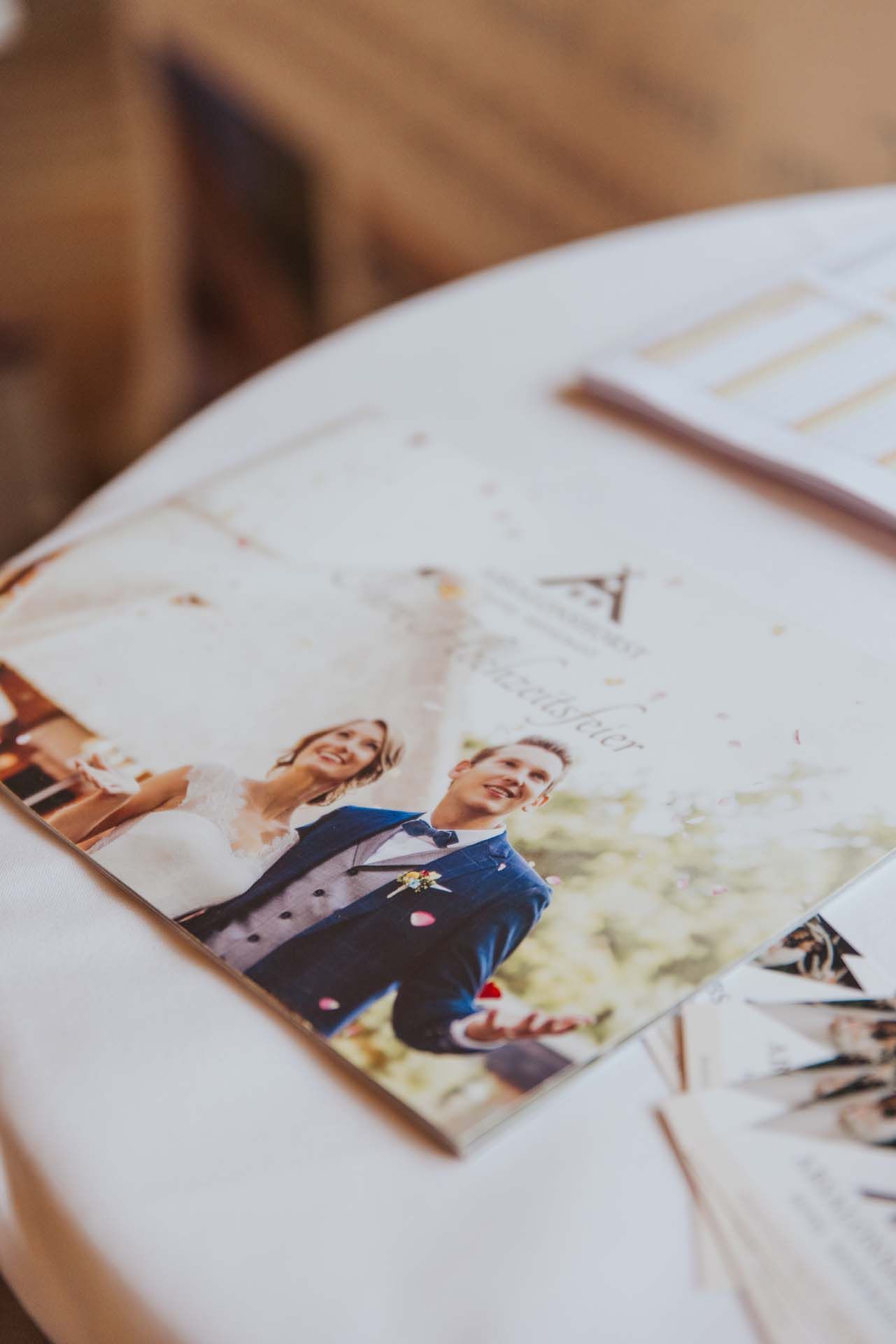 Hochzeitsfoto auf einem Tisch; lächelndes Brautpaar, Konfetti, im Freien.