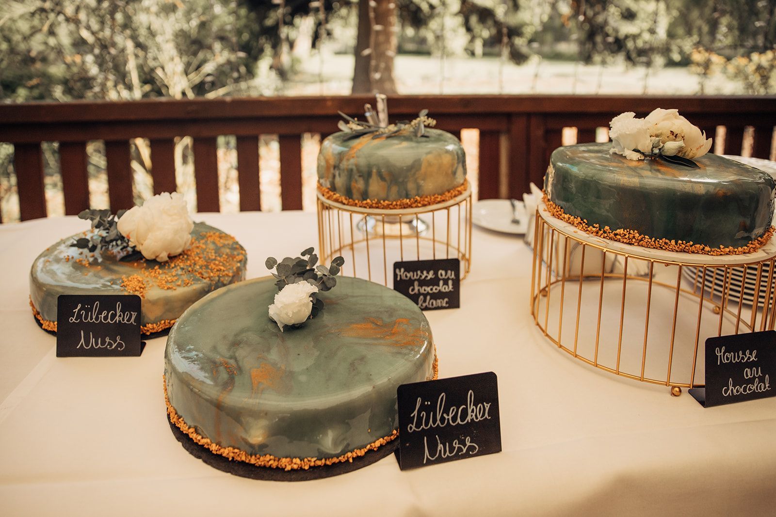 Auf einem Tisch stehen vier runde Kuchen mit blaugrüner Glasur und Dekorationen.
