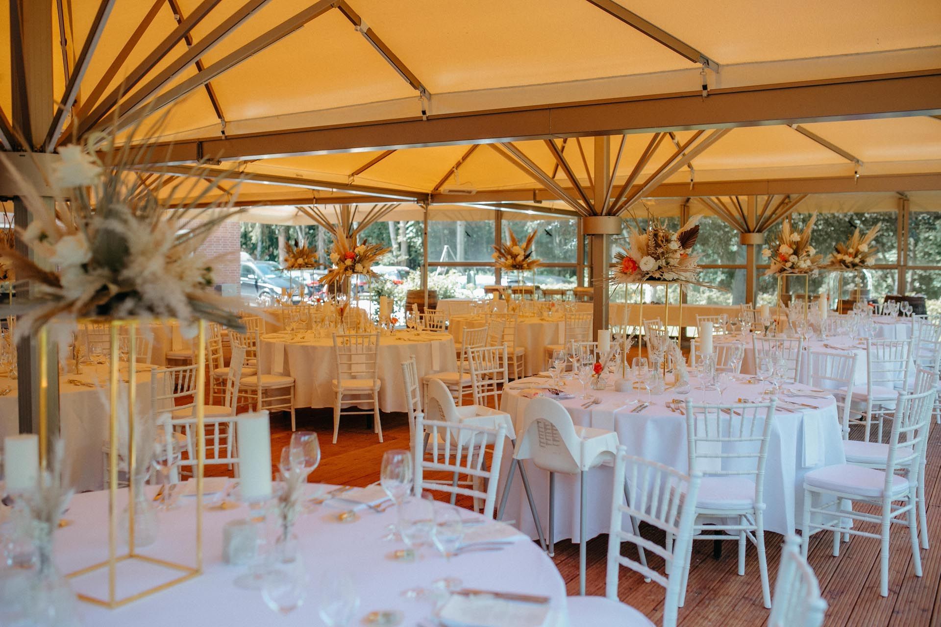 Hochzeitsempfang, Tische mit weißer Tischwäsche und Stühlen unter einem hellbraunen Baldachin.