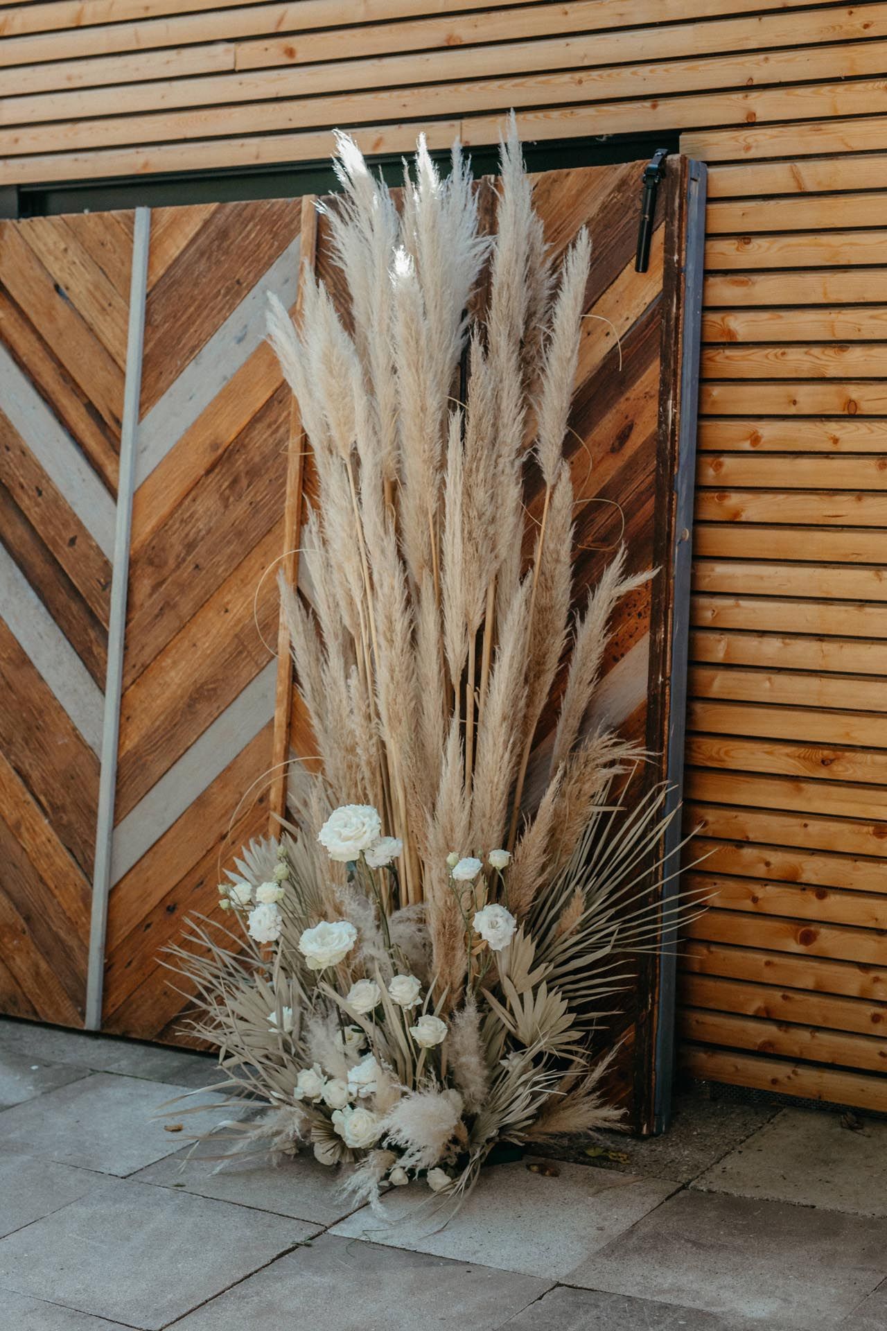 Getrocknetes Pampasgras und weiße Blumen auf einem Holzhintergrund, eine Hochzeits- oder Eventdekoration.