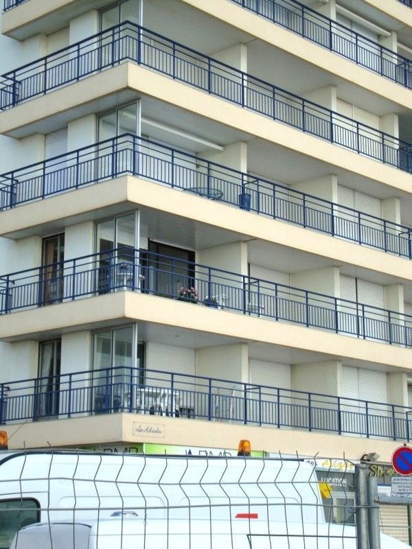 Immeuble d'appartements moderne avec balcons bleus et hall d'entrée couvert